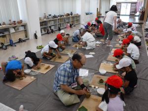 土器づくりをする小学生を手伝う応援団（写真）