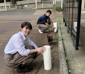 高校生が外で行灯を設置している様子（写真）