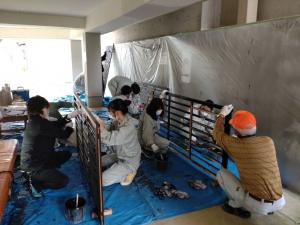 格子の塗装作業の様子　町内会の有志の皆さんと上越総合技術高等学校の生徒さんが協力して作業しています（写真）