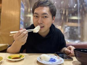 好物のイカの寿司を食べている様子（写真）