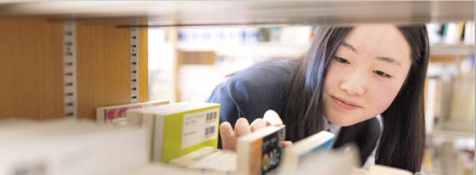 やさしく微笑んで本を選ぶ美少女（写真）