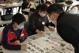 指導を受けて紙芝居の文字の色塗りをしています（写真）