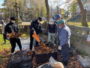集めた落ち葉を発効促進用の木桶に移す参加者の様子（写真）