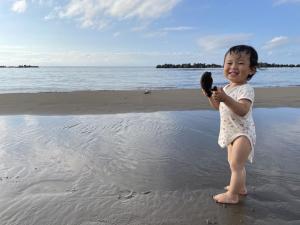 海で泥遊びをするにっこり笑顔の子ども（写真）