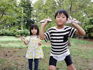 ニジマスをつかんでポーズをとる子供の写真