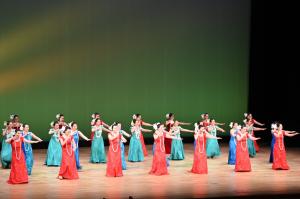 赤、青、緑のドレスを着た人達がフラダンスを踊っている様子（写真）