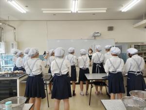 講師から料理の説明を聞く生徒（写真）