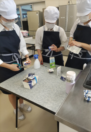 笹寿司に使う牛乳パックをハサミで切る生徒（写真）