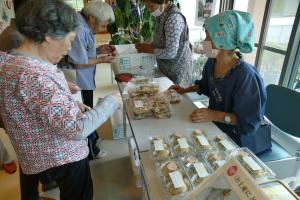 地元加工グループと談笑しながら商品を購入する人の様子（写真）