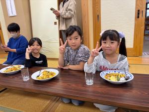 カレーを目の前にピースサインをする子どもの様子（写真）