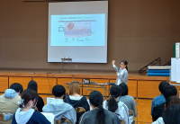 スライドを示す講師（写真）