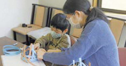 親子でクラフトバンドを組み立てる様子（写真）