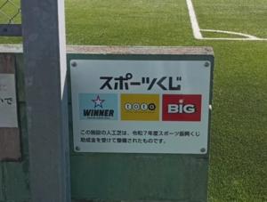 人工芝が、令和7年度スポーツ振興くじ助成金を受けて整備されたことを示すPR看板（写真）