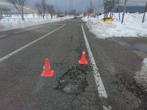 舗装の穴の目印に三角コーンが置かれている様子(参考写真)