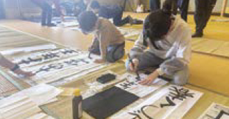 子どもたちが真剣に書初めをする様子（写真）