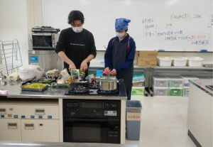 信田さんの調理を手伝う生徒（写真）