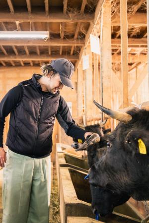 笑顔で牛の様子を見る水澤洸大さん（写真）