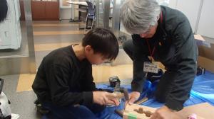 スタッフから補助を受けながら木工に取り組む子ども（写真）