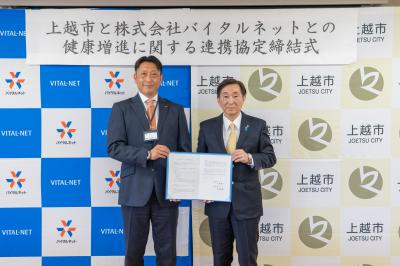 署名した連携協定書を掲げる株式会社バイタルネット上越支店長(左)と上越市長(写真)