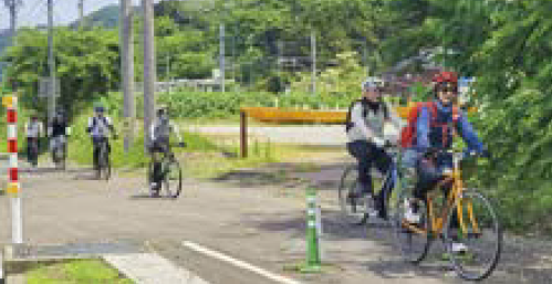 自転車で一列になって走るツアー参加者(写真)