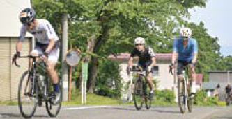 上り坂で自転車をこぐ選手たち（写真）