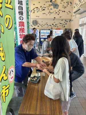 小学生がお母さんから購入する様子（写真）